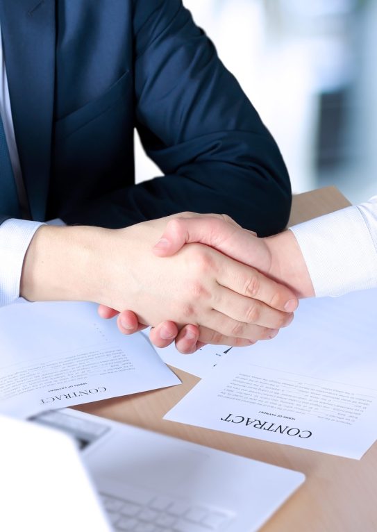 Close-up image of a firm handshake between two colleagues after signing a contract